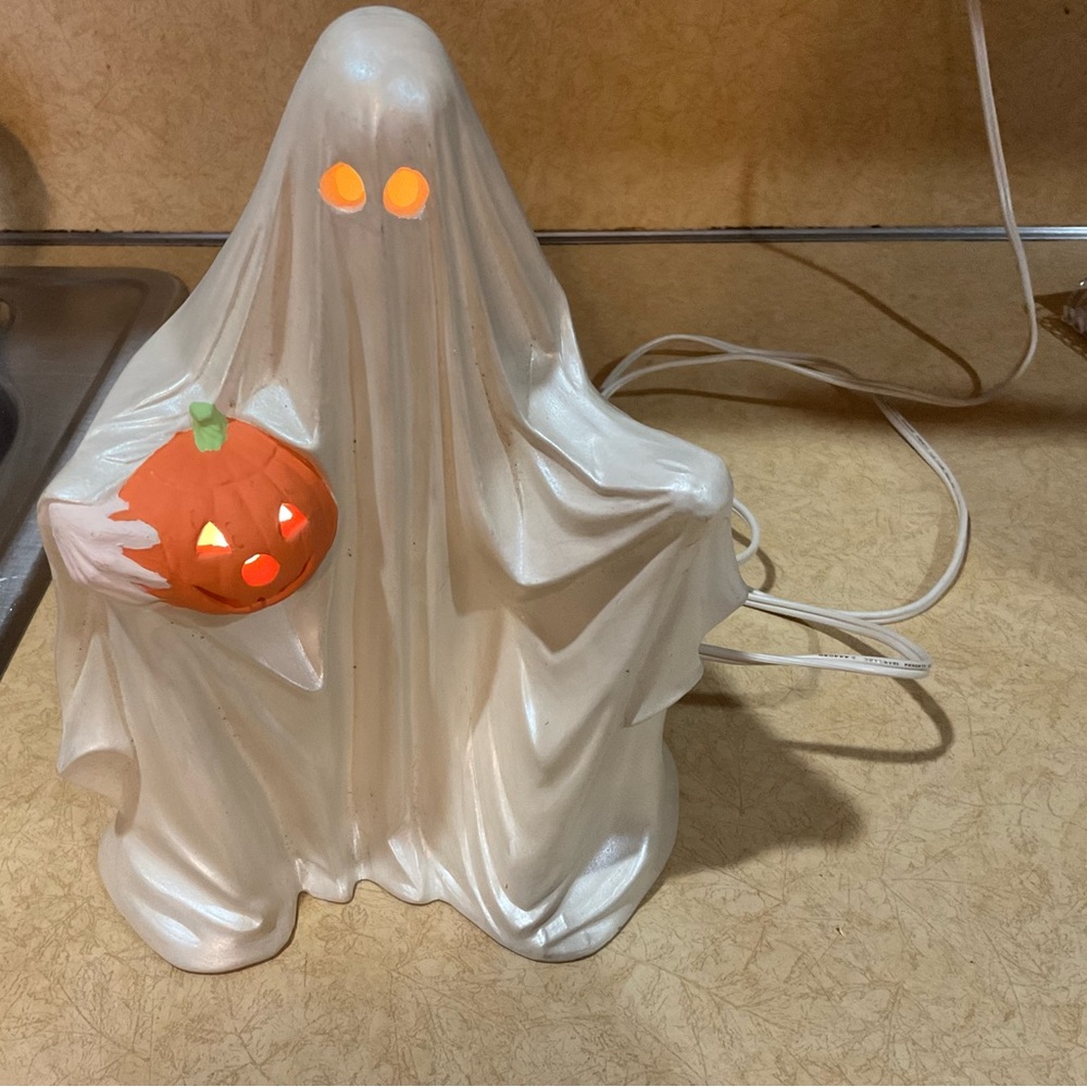 Handcrafted: Ceramic white ghost holding small pumpkin with detachable cord.